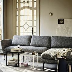 a man standing in front of a couch looking out the window