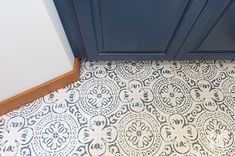 a bathroom with a blue cabinet and white tile flooring next to a toilet in the corner