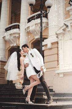 a man and woman are walking down the stairs in front of a building with their arms around each other