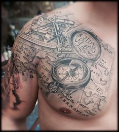 a man's chest covered in tattoos with an old map and compass on it