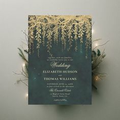 an elegant wedding card with gold foil and greenery on the front is surrounded by string lights