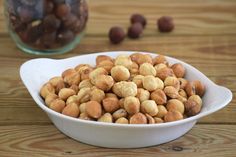 a white bowl filled with nuts on top of a wooden table