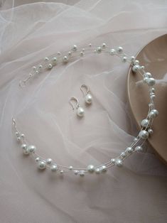 a necklace and earring set with pearls on a white table cloth next to a plate