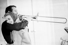 black and white photograph of a man playing the trombone with a woman standing next to him