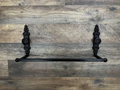 a black iron towel rack on a wooden wall