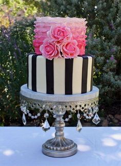 a black and white striped cake with pink flowers on top is sitting on a table