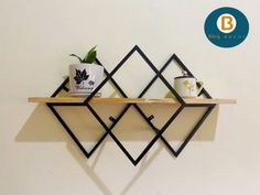 a shelf with two mugs on it next to a potted plant and coffee cup