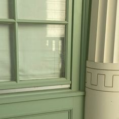 a white vase sitting next to a green window