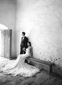 a man and woman are standing next to each other on a bench in an old building