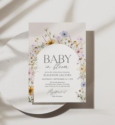 a baby is born announcement card with flowers on the front and bottom, in white paper