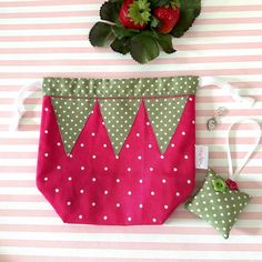 a pink and green bag with polka dots on it next to a potted plant