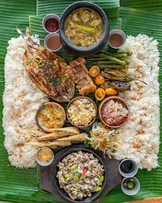 an overhead view of various foods on a green plate with rice and sauces in bowls