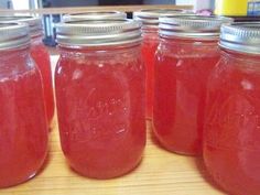 four jars filled with red liquid sitting on top of a table