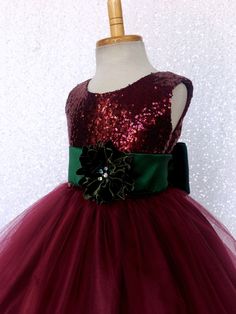 Have your little girl sparkle along with the Christmas lights with this gorgeous dress! The sleeveless dress comes with a fully lined sequence top. A zipper can be found going down the back of the dress. The dress is followed by a double layer of tulle that is lined with fishing line to give the bottom of it's skirt it's wavy texture. Underneath both layers of tulle are two layers of lining, one plain and a final layer of lining with crinoline attached for fullness. Finish the dress off with a d Princess Style Tulle Gown For Christmas, Christmas Princess Tulle Gown, Princess Gown For Christmas Dress-up, Christmas Princess Gown For Dress-up, Princess Style Christmas Gown For Dress-up, Christmas Princess Dress-up Gown, Green Princess Dress For Birthday And Christmas, Christmas Princess Dress With Sequins For Dress-up, Princess Christmas Gown For Festive Occasions