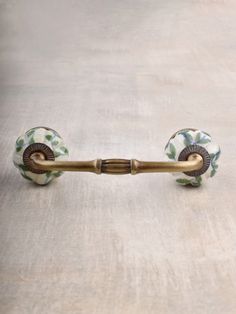 an old fashioned brass handle on a white tablecloth with green and blue floral designs