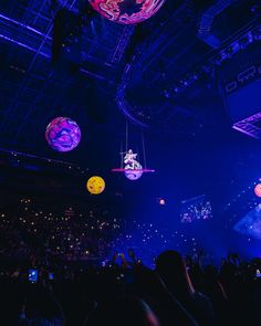 the audience at a concert is looking up at colorful lights and decorations hanging from the ceiling