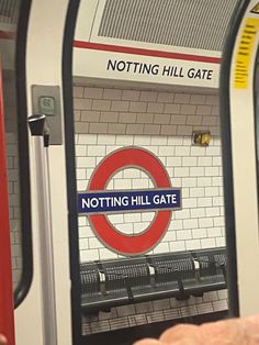 there is a red and white sign that says notting hill gate on the wall