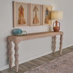 a wooden table sitting next to a wall with three pictures on it's side