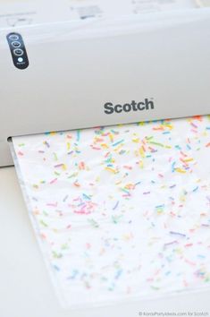 a white machine with sprinkles on it sitting next to a paper towel