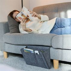 a woman laying on a couch reading a book