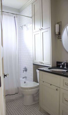 a white toilet sitting in a bathroom next to a sink and bathtub under a mirror