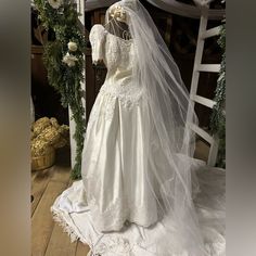 a wedding dress on display in front of a wooden table with flowers and greenery