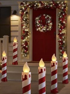 lighted candles are lined up in front of a red and white door decorated for christmas