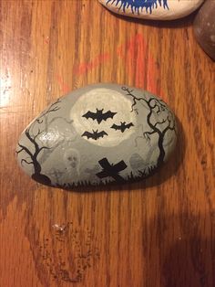 a rock with bats painted on it sitting on top of a wooden table next to a pair of shoes