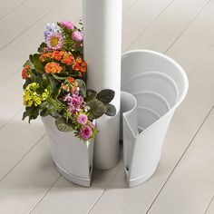 two white vases with flowers in them sitting on the floor next to each other