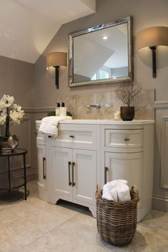 a bathroom with a large mirror above the sink and a basket on the floor next to it