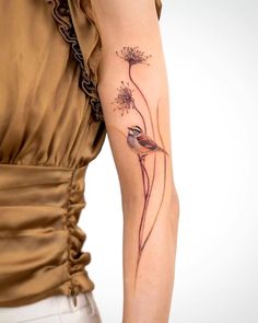 a woman's arm with a bird and flower tattoo on the back of her left arm