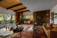 a living room filled with furniture and lots of windows next to a wooden floored wall