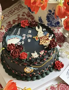 a decorated cake sitting on top of a table next to red flowers and paper decorations