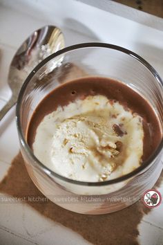 a glass bowl filled with ice cream on top of a white counter next to a spoon