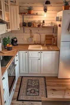 a small kitchen with white cabinets and wood flooring is pictured in this image from the doorway