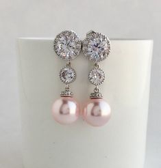 Simply gorgeous !! I've created these elegant cubic zirconia and Swarovski pearl bridal earrings in rhodium plated brass setting. Earrings feature large 12mm Swarovski Blush Pink pearls that dangle from brilliant cut clear cubic zirconia with halo setting 12mm ear stud and round connector. Halo setting gives a brilliantly beautiful effect. Total length of the earrings is 3.8 cms. For matching necklace click: https://www.etsy.com/listing/761211024/large-pink-pearl-bridal-necklace-blush?ref=shop_h Elegant Pink Cubic Zirconia Bridal Earrings, Elegant Pink Crystal Bridal Earrings, Pink Cubic Zirconia Crystal Earrings For Wedding, Pink Pearl Bridal Earrings For Wedding, Pink Pearl Drop Earrings For Wedding, Pink Pearl Earrings For Wedding, Wedding Cubic Zirconia Round Pearl Earrings, Round Cubic Zirconia Pearl Earrings For Wedding, Wedding Round Cubic Zirconia Pearl Earrings