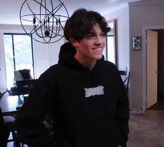 a young man in a black hoodie is smiling