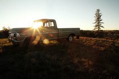 the truck is parked in the field with the sun shining on it's side