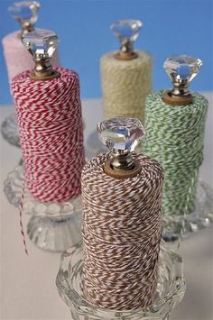 three spools of twine sitting on top of each other in glass containers