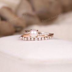 two rings with pearls and diamonds on top of a white surface in front of a dog