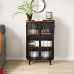 a living room with a couch, mirror and black cabinet