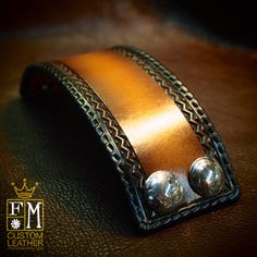 a leather cuff with two metal balls on it