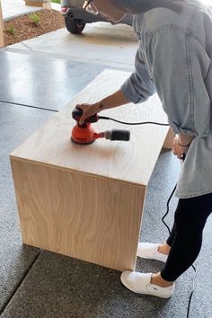 a woman sanding the top of a table with an electric polisher on it