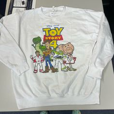 the toy story 4 sweatshirt is sitting on top of a table next to some shoes