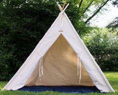 a teepee sitting in the grass near some trees