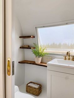 a bathroom with a toilet, sink and shelves in it's corner area next to a window