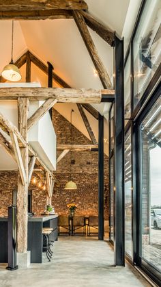 an open kitchen and dining area with exposed beams in the ceiling, along with large windows