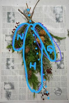 a piece of paper that has been decorated with blue string and pine cones on it