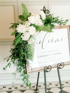 a welcome sign with greenery and white flowers