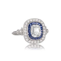 A stunning Diamond and Sapphire engagement ring featuring a 1.07 carat elongated antique cushion cut diamond with J color and VS2 clarity. The triple wire shank leads to one accenting stone on either side, with beautiful milgrain. The detailed under-gallery sits under a halo of diamonds and sapphire, both highlighted by fine milgrain along the bezel. ✦ DIAMOND SPECIFICATIONS: Diamond Cut: Antique Cushion Cut, Cushion Cut Diamond Clarity: VS2 Diamond Color: J Color Diamond Weight 1.07 Carats ✦ EN Diamond And Sapphire Engagement Ring, Sapphire Engagement Ring Halo, Antique Cushion Cut Diamond, Antique Cushion Cut, Estate Diamond Jewelry, Cushion Cut Diamond Ring, Antique Cushion, Cushion Cut Diamond, Vs2 Diamond